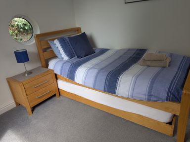 A bedroom with a bed, nightstand, lamp, and towels at Hawthorn Cottage St Teath