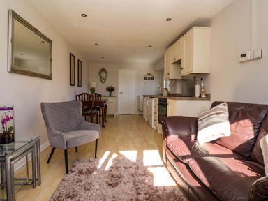 A living room with a sofa and dining table at Cartwheel Cottage in Yearsley