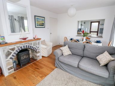 A living room with a gray sofa and stone fireplace adjacent to a dining area set with dishes at Valley High in Solva