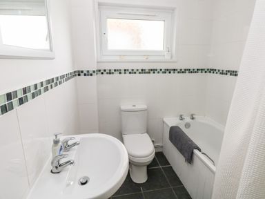 A bathroom with a sink a toilet a bathtub with a towel and a window at Valley High in Solva