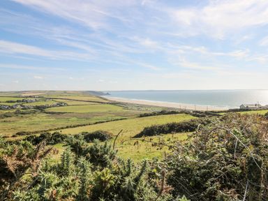 A coastal landscape with green fields houses and a beach beside the sea at Valley High in Solva