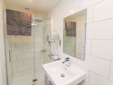 A bathroom with a sink and mirror beside a glass enclosed shower at 3 Elm Cottage in Carhampton