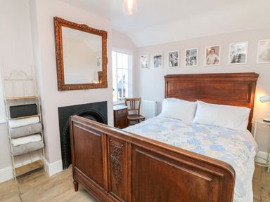 A bedroom with a wooden bed and headboard a wooden chair and framed pictures above the bed at 3 Elm Cottage in Carhampton