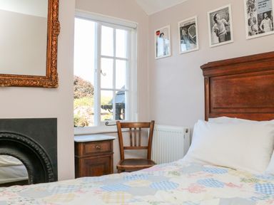 A bedroom with a wooden bed wooden chair wooden nightstand window and framed pictures on the wall at 3 Elm Cottage in Carhampton