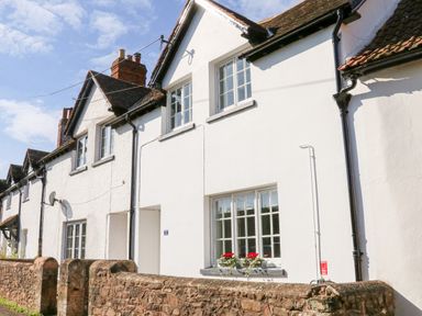 A row of white terraced houses with tiled roofs and stone wall at 3 Elm Cottage in Carhampton