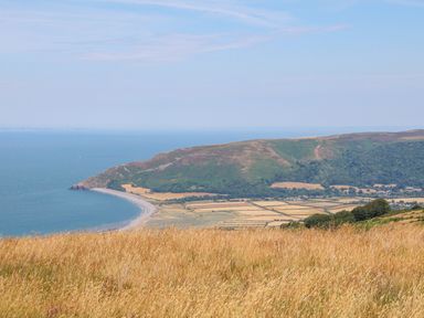 A coastal landscape with a curved beach fields and hills at 3 Elm Cottage in Carhampton