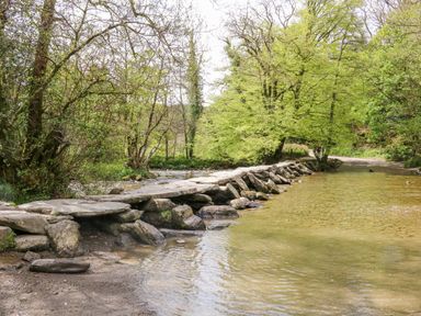 A shallow river with flat stones forming a crossing and trees along the banks at 3 Elm Cottage in Carhampton