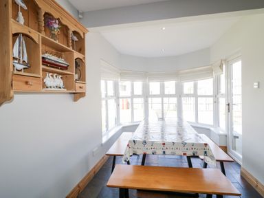 A dining area with a picnic style table and benches near large windows at SeaShells in Castlerock