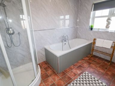 A bathroom with a shower enclosure bathtub towel rack with towels and a window with decor at SeaShells in Castlerock
