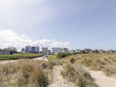 A sandy path through grass dunes leading to buildings under a clear sky at SeaShells in Castlerock