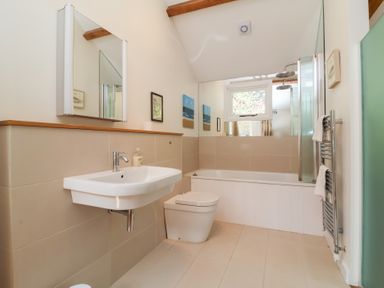 A bathroom with a sink, toilet, and bath tub at Old Maids Cottage in Woolacombe