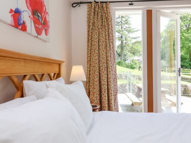 A bedroom with a bed and curtains at Old Maids Cottage in Woolacombe