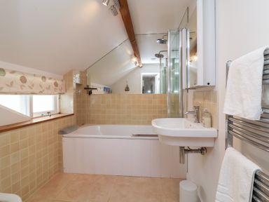 A bathroom with a bathtub and sink at Old Maids Cottage in Woolacombe