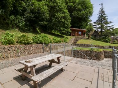 An outdoor area with a picnic table and stone wall at Old Maids Cottage in Woolacombe