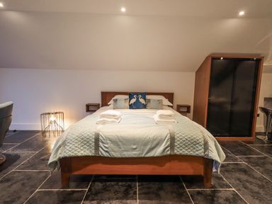A bedroom with a double bed folded towels on the bed and a wardrobe at The Boat House at Louper Weir in Bowness-On-Windermere