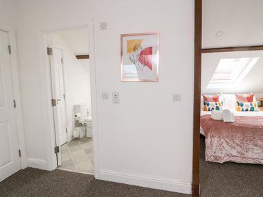 A view of a bathroom with a toilet and a bedroom with a bed and pillows at The Old Sweet Shop in Alnwick