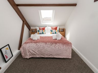 A bedroom with a bed under a skylight and wooden side tables at The Old Sweet Shop in Alnwick