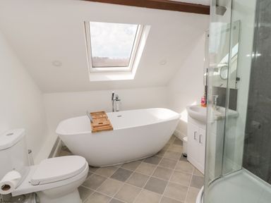 A bathroom with a toilet bathtub sink and shower under a skylight at The Old Sweet Shop in Alnwick