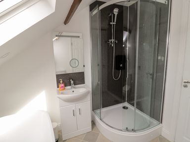 A bathroom with a glass shower enclosure a white sink with cabinet and a mirror at The Old Sweet Shop in Alnwick