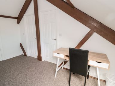 A room with two white doors a desk with drawers a black chair and exposed brown wooden beams at The Old Sweet Shop in Alnwick