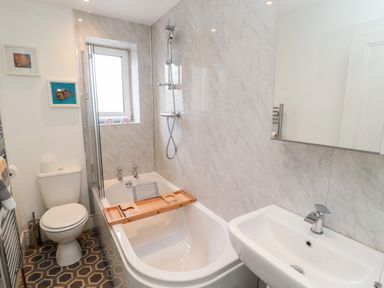 A bathroom with a bathtub shower toilet sink and framed pictures on the wall at The Old Sweet Shop in Alnwick
