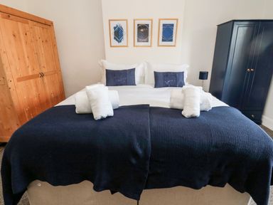 A bedroom with a double bed white and navy bedding wooden and black wardrobes at The Old Sweet Shop in Alnwick