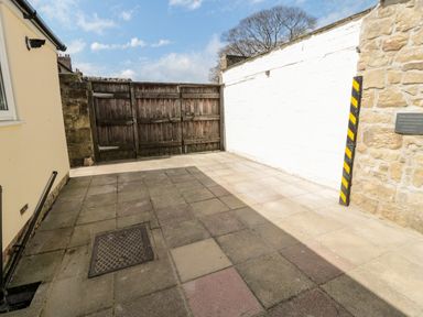 A paved courtyard area with a wooden gate and stone walls at The Old Sweet Shop in Alnwick