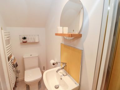 A small bathroom with a toilet sink mirror and towel rack at The Old Sweet Shop in Alnwick