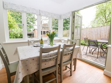 A dining area with a table set for four and an open door to a patio at 3 Painters Field in Quenington Near Cirencester