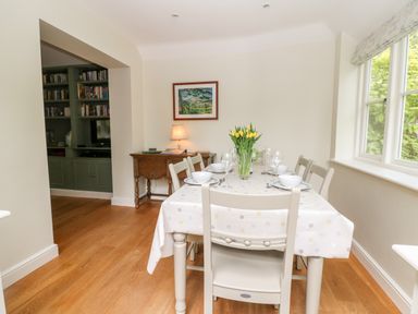 A dining room with a table set for six and yellow flowers in a vase at 3 Painters Field Quenington Near Cirencester