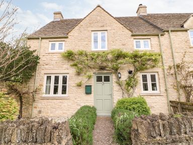 A stone cottage with green door and windows and plants growing on the wall at 3 Painters Field in Quenington Near Cirencester