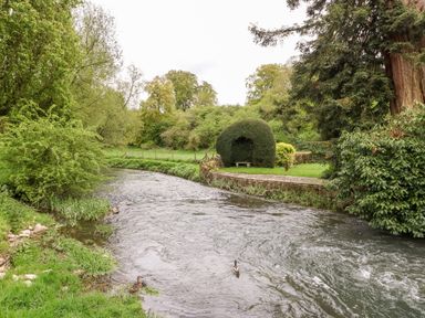 A river with ducks surrounded by trees and bushes near 3 Painters Field in Quenington Near Cirencester