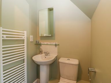 A bathroom with a pedestal sink a toilet a mirror and a white towel radiator at 3 Painters Field in Quenington Near Cirencester