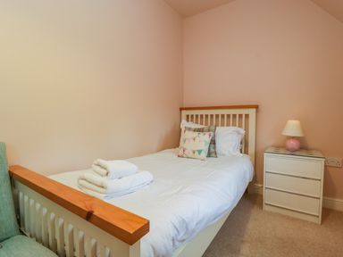 A single bed with white linens and pillows next to a white bedside table with a lamp in a bedroom at 3 Painters Field Quenington Near Cirencester