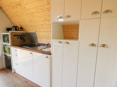 A kitchen with white cabinets a sink stovetop microwave and small refrigerator at Seren in Llandrindod Wells