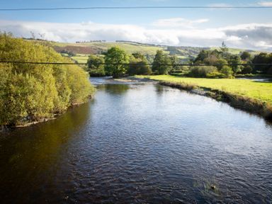 A river with trees and hills in the background at Bwthyn Bach Brefi