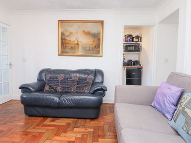 A living room with leather and fabric sofas and a framed painting above the sofa at Tanyfron Holiday Studio in Bryngwran near Gwalchmai