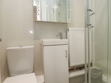A bathroom with a toilet sink cabinet radiator and glass shower door at Tanyfron Holiday Studio in Bryngwran near Gwalchmai