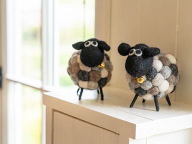 Two decorative woolen sheep figures on a white shelf near a window at Onnen in Oakford near Aberaeron
