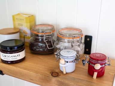 Jars of preserves and containers on a wooden shelf at Onnen in Oakford near Aberaeron