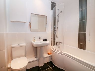A bathroom with a toilet sink mirror bathtub and shower at 10 Pen Llanw Tides Reach in Rhosneigr