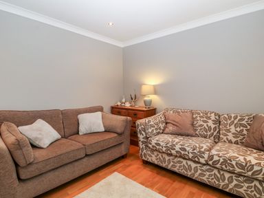 A living room with two sofas a wooden chest of drawers and a table lamp at 10 Pen Llanw Tides Reach in Rhosneigr