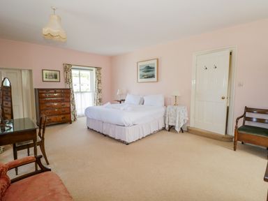 A bedroom with a bed two side tables a chest of drawers a desk and chairs at The White House in Cartmel