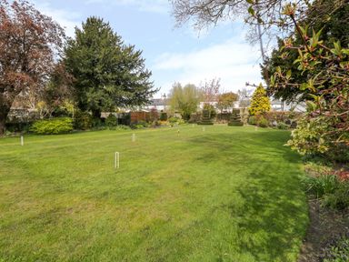 A garden with a croquet set on a lawn and trees and shrubs at The White House in Cartmel