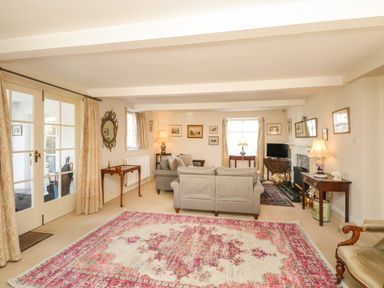 A living room with sofas a patterned rug tables lamps a fireplace and framed pictures at The White House in Cartmel