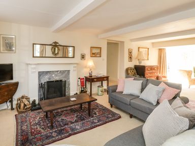 A living room with a fireplace gray sofas and a wooden coffee table on a patterned rug at The White House in Cartmel