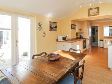 A kitchen with wooden table and chairs a microwave and oven in a room with yellow walls at The White House in Cartmel
