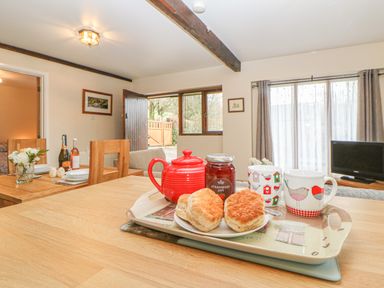 A dining area with tea set and scones on a wooden table at Hilly Field Barn in Yelverton