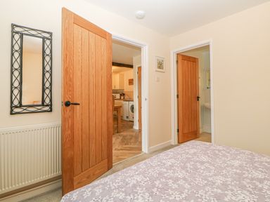 A bedroom view showing two wooden doors one leading to a kitchen and the other to a bathroom at Hilly Field Barn in Yelverton
