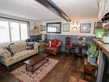 A living room with a sofa armchair wooden coffee table and decorative plants at The Old Paper Shop in Tewkesbury